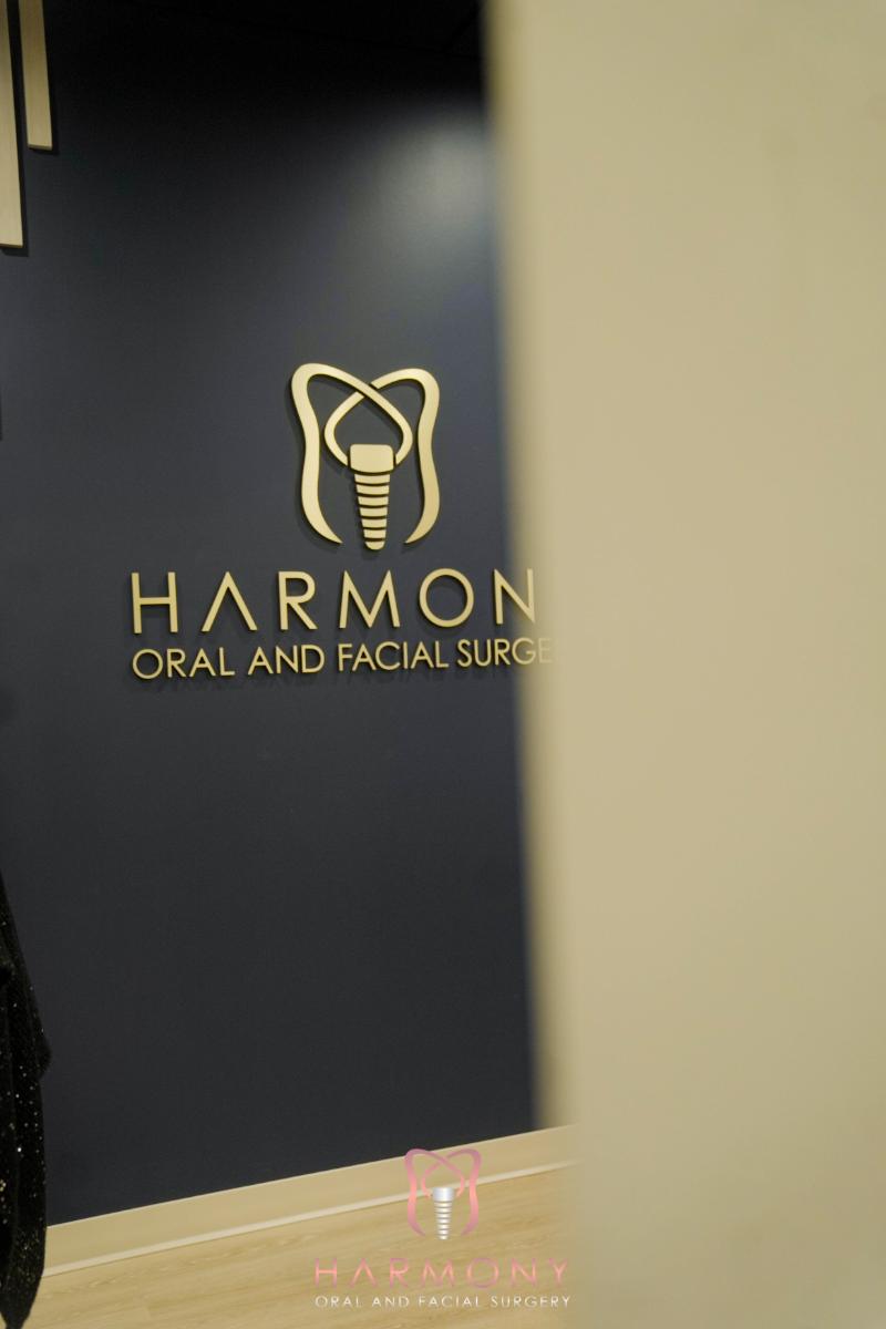 The image shows a sign with the text HARMON DENTAL AND FACIAL SURGERY on a wall, suggesting this is the name of a dental and facial surgery practice.