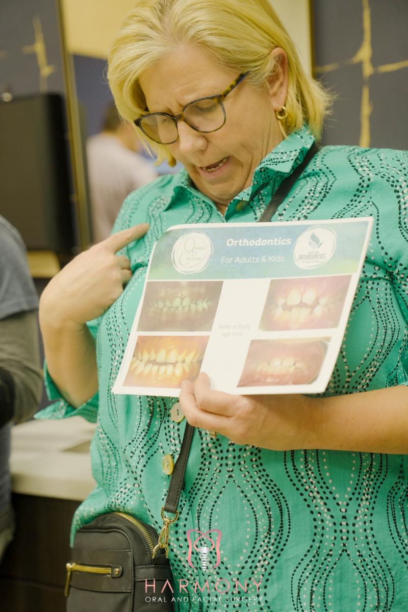 The image shows a woman holding up a sign with pictures of teeth, possibly indicating dental services or information.
