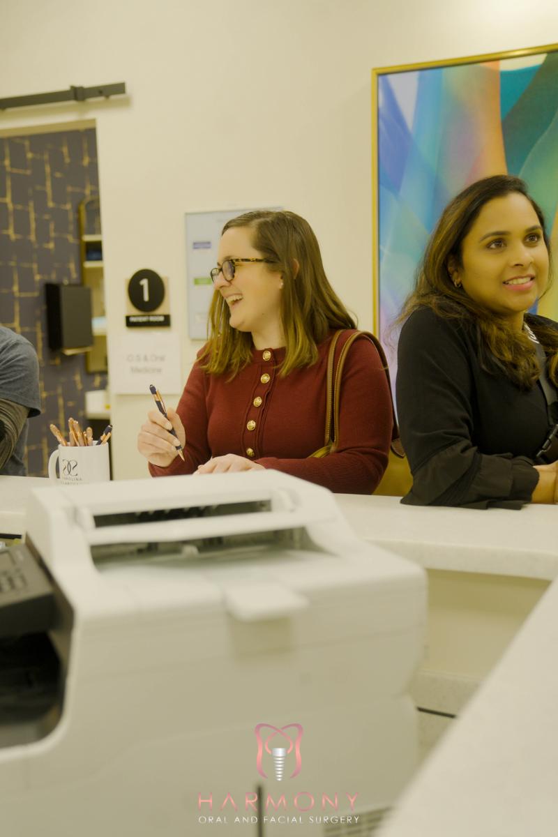 Two women standing at a counter with a printer behind them.