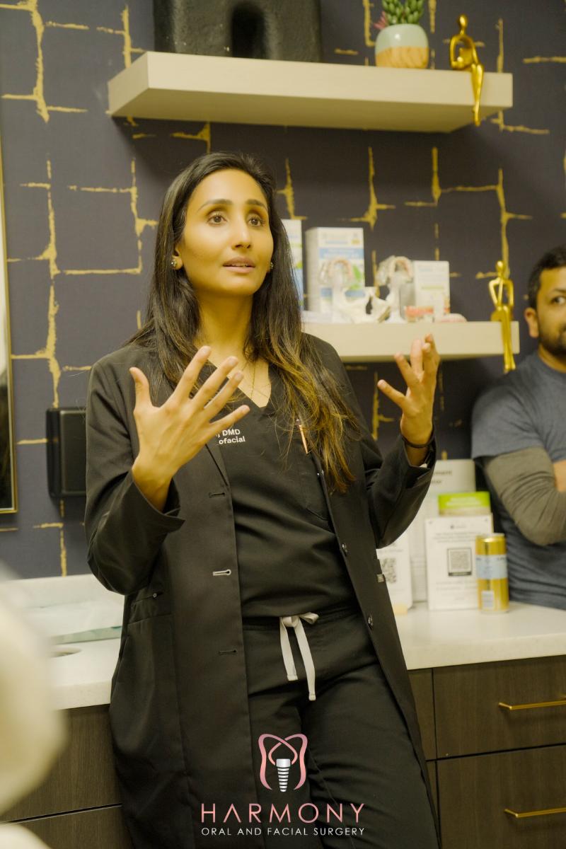 A woman standing in front of a store display with her hand on her chin, wearing scrubs, in an indoor setting.