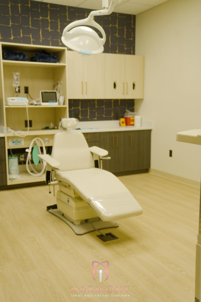 The image depicts a well-equipped dental office with a modern dental chair and various medical equipment.