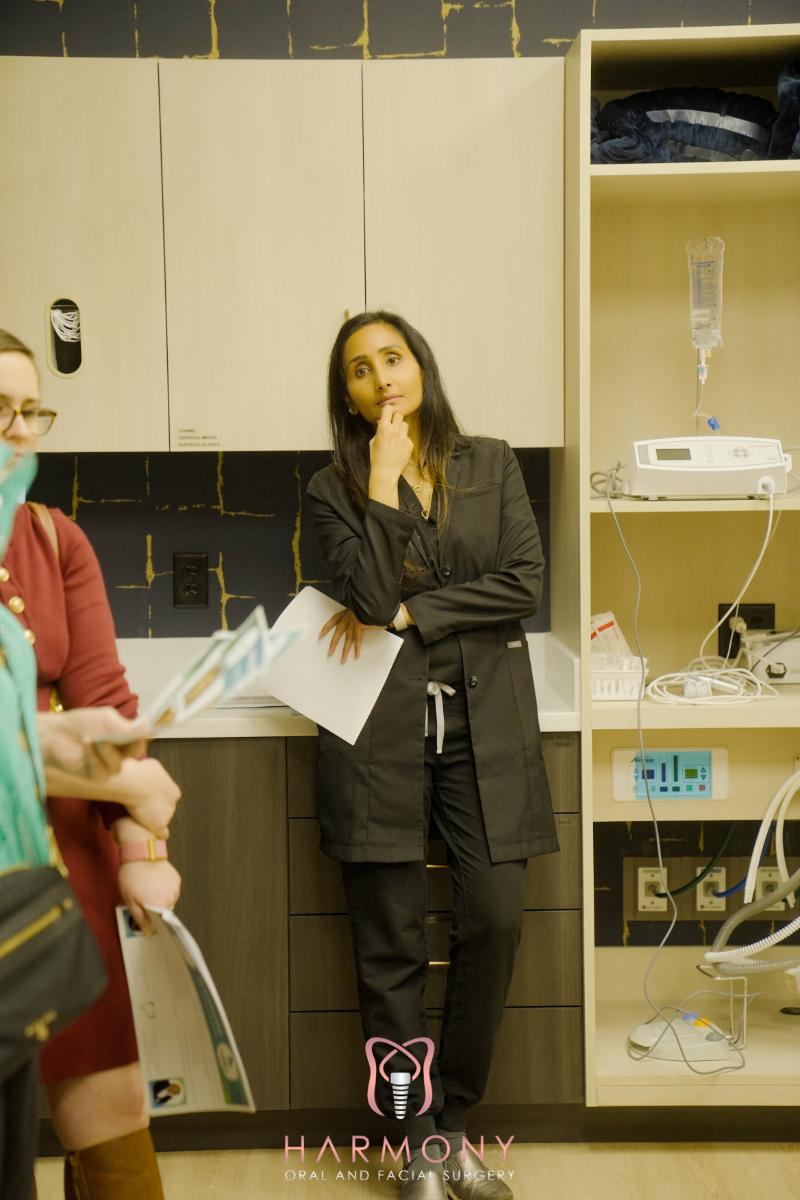 A woman leaning against a counter with papers in hand, standing in front of shelves stocked with medical equipment.