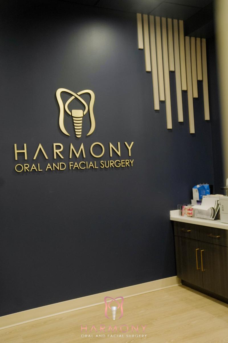 The image shows an interior view of a dental practice with a sign featuring a toothbrush logo, a blue wall, and a partial view of a reception area.